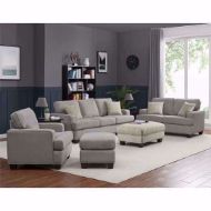 A modern living room featuring a light gray sectional sofa set with an ottoman, armchair, and loveseat on a white rug. The room has gray walls with a navy blue lower wall panel, hardwood floors, and is decorated with a bookshelf, lamps, and wall art, with natural light coming through the window.